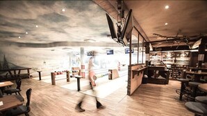 Un restaurant moderne avec un plancher en bois, un bar et une fresque murale.