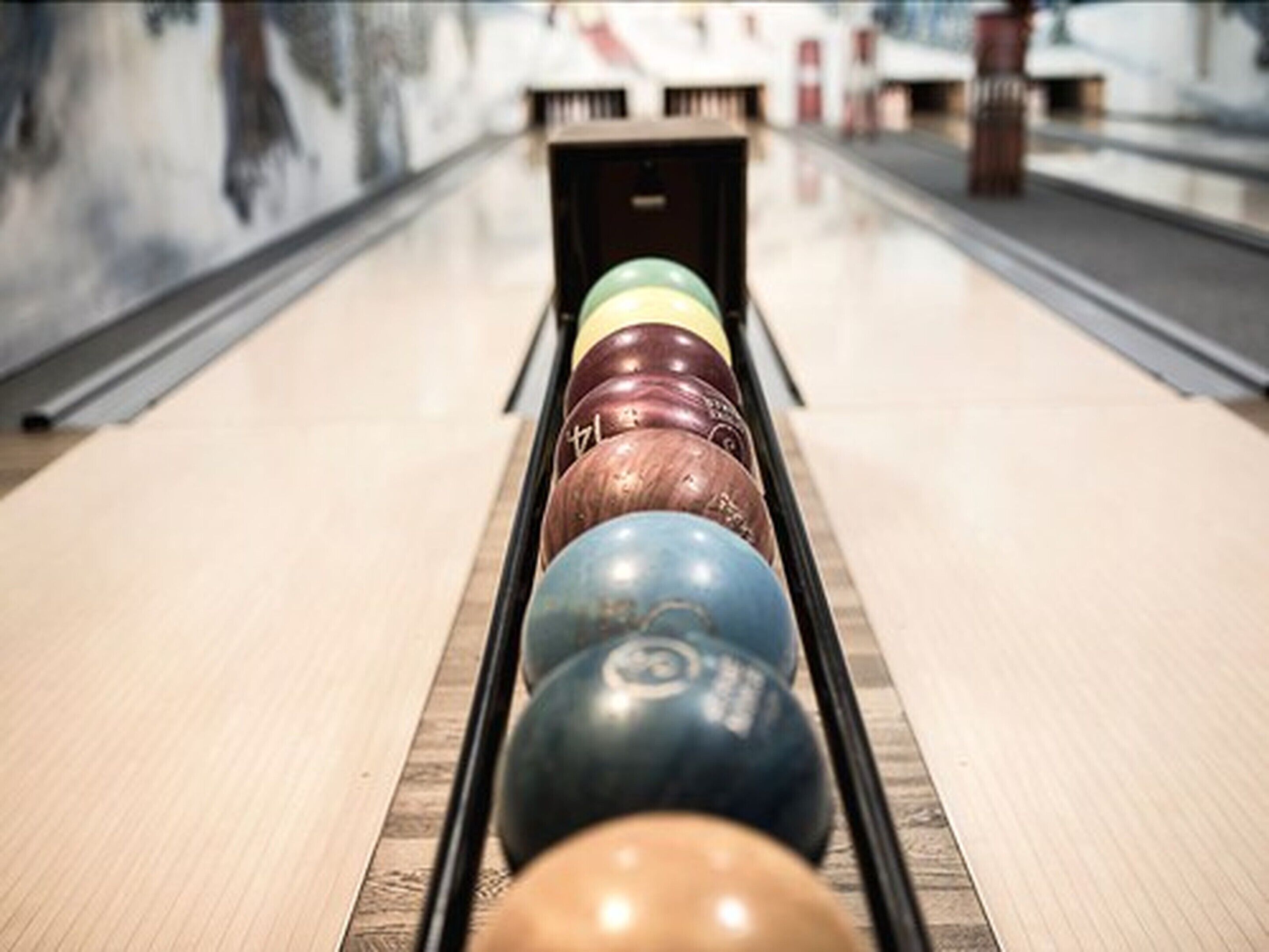 Une salle de bowling avec une piste et des boules de bowling alignées.