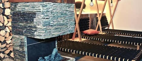 Un cuarto acogedor con chimenea de piedra, una cama con estructura de madera y un candelabro colgante.
