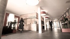 Un espace d’accueil avec un comptoir en bois portant l’inscription « RÉCEPTION », et une personne qui se déplace à l’arrière-plan.