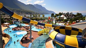 A water park with a large slide, multiple pools, and a mountainous backdrop. - B&B Mon Rêve (Port-Valais)