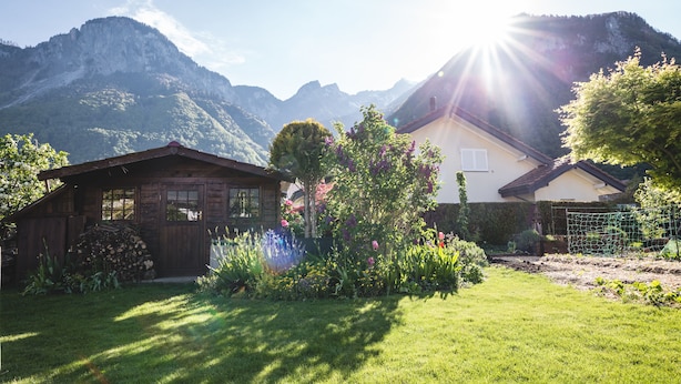 A house with a garden in front, surrounded by mountains. - B&B Mon Rêve (Port-Valais)