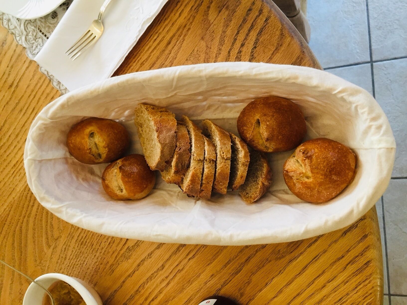 A basket of bread rolls on a wooden table.