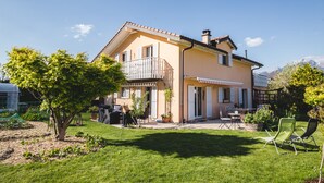 A two-story house with a balcony, a garden, and outdoor furniture. - B&B Mon Rêve (Port-Valais)