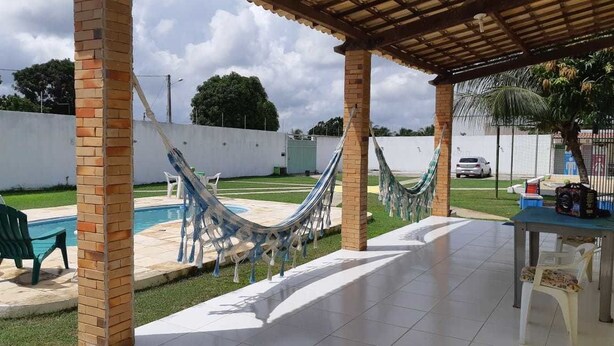 A covered patio area with a hammock, a pool, and outdoor seating. - Chacara So Alegria em Parnamirim (Parnamirim)
