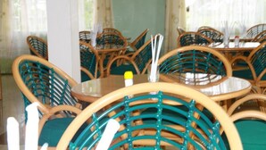 A restaurant interior with round tables and wicker chairs.
