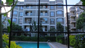 A multi-story residential building with balconies, a swimming pool, and surrounding greenery. - Celestial Luxury Homestay (Syokimau)