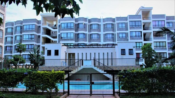 A multi-story hotel with balconies, a swimming pool, and a gated entrance. - Celestial Luxury Homestay (Syokimau)