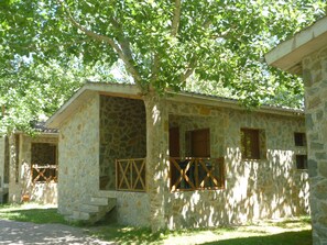A stone building with a balcony, a window, and a door. - Camping Pirinenc (Campdevanol)
