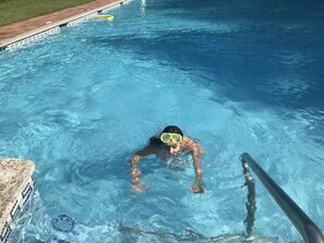 A swimming pool with clear blue water, a diving board, and a tiled edge. - Camping Pirinenc (Campdevanol)