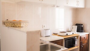 Eine Küche mit weißen Schränken, einem Toaster, einer Kaffeemaschine und einer Mikrowelle.