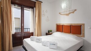 Ein Hotelzimmer mit Bett, Vorhängen, einem Fenster und Wandbildern.