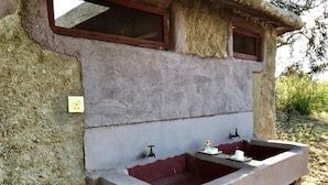 Un bagno esterno rustico con due lavandini, una finestra e una presa di corrente.
