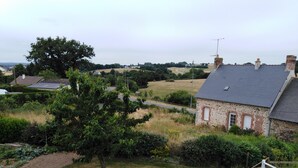 A stone house with a sloped roof, surrounded by a grassy yard and a large tree. - Chambres d'hôtes le Pot au Lait (Villaines-la-Juhel)
