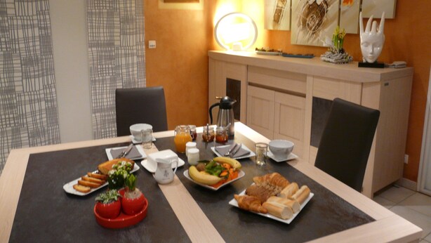 A dining table set with breakfast items, a coffee pot, and a framed picture on the wall. - Chambres d'hôtes le Pot au Lait (Villaines-la-Juhel)