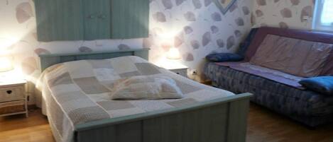 Un dormitorio con cama, mesita de noche, cómoda y ventana.