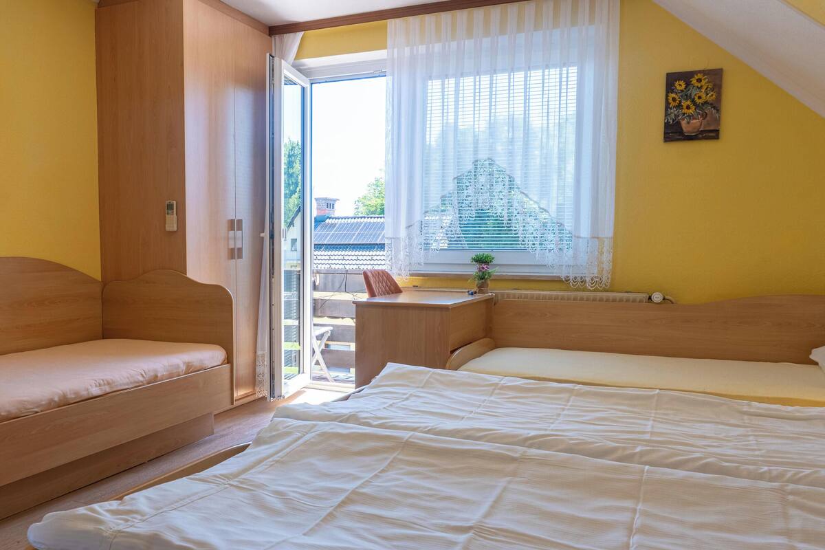 Ein Schlafzimmer mit einem Bett, einer Couch, einem Schreibtisch und einem Fenster mit Vorhängen.