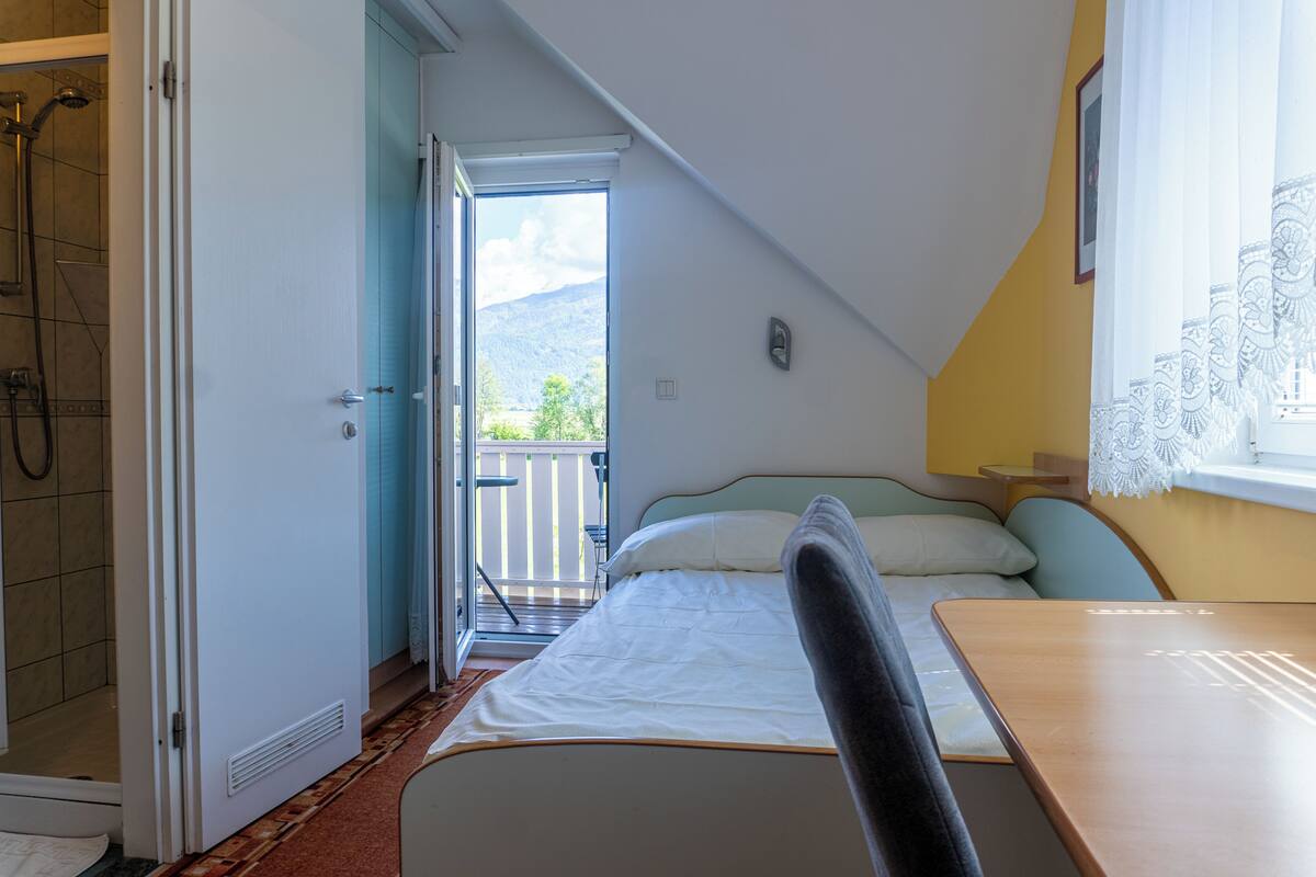Ein Schlafzimmer mit Bett, Tisch, Stuhl, Dusche und einem Balkon mit Blick.