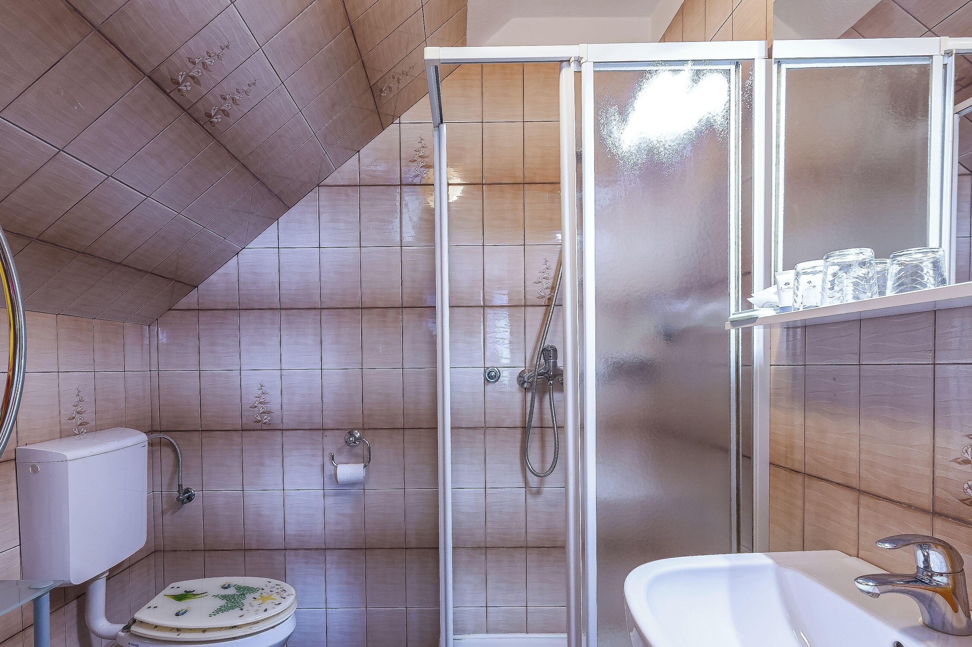 A bathroom with a toilet, shower, and sink.