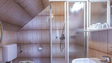 A bathroom with a toilet, shower, and sink.