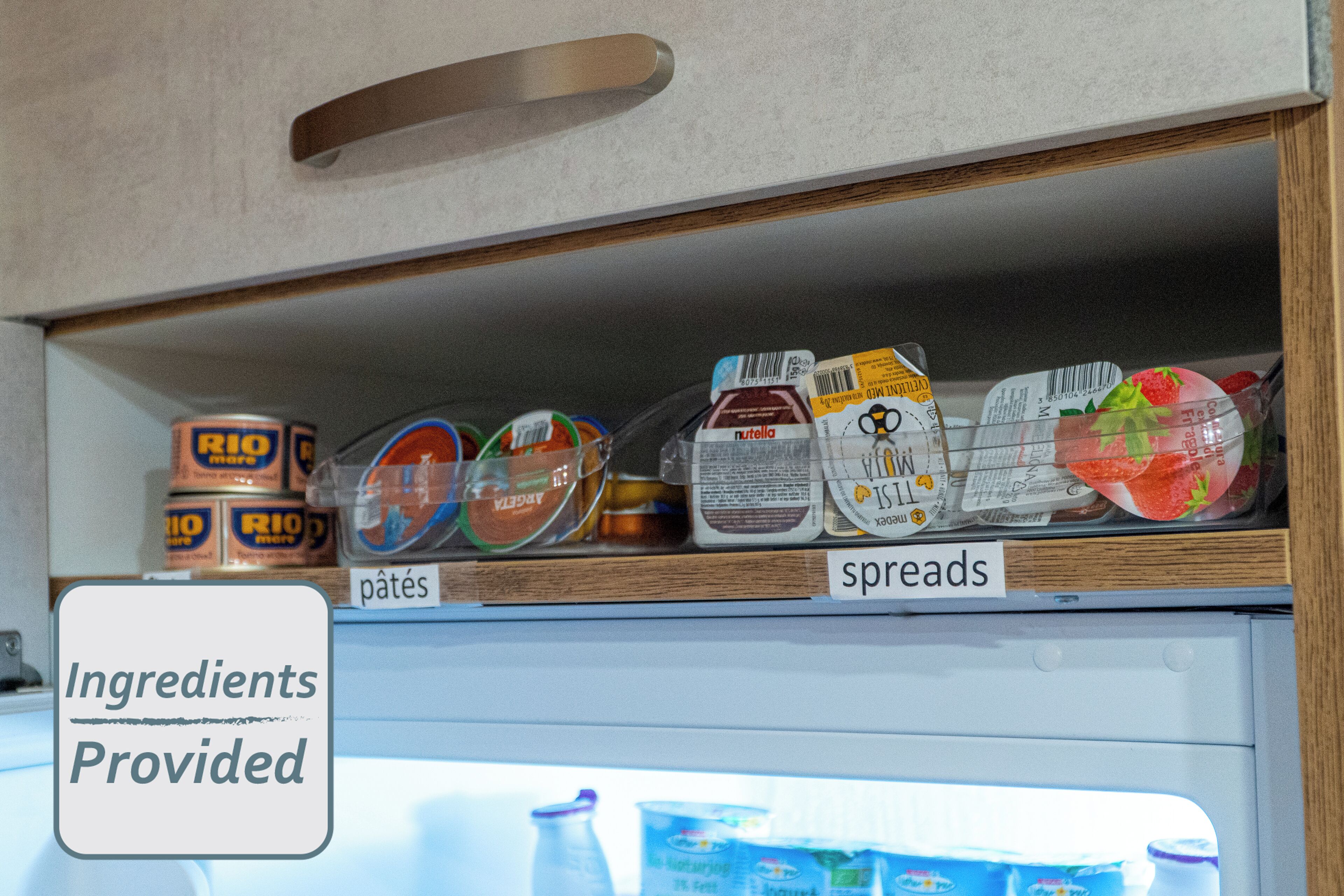 A kitchen pantry with labeled shelves for spreads and pâtés, and a sign indicating ingredients are provided.