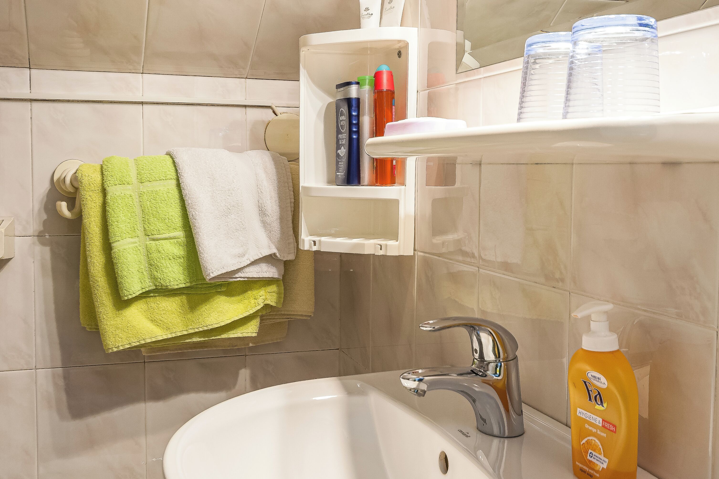 A bathroom with a sink, a mirror, and a towel rack with multiple towels.