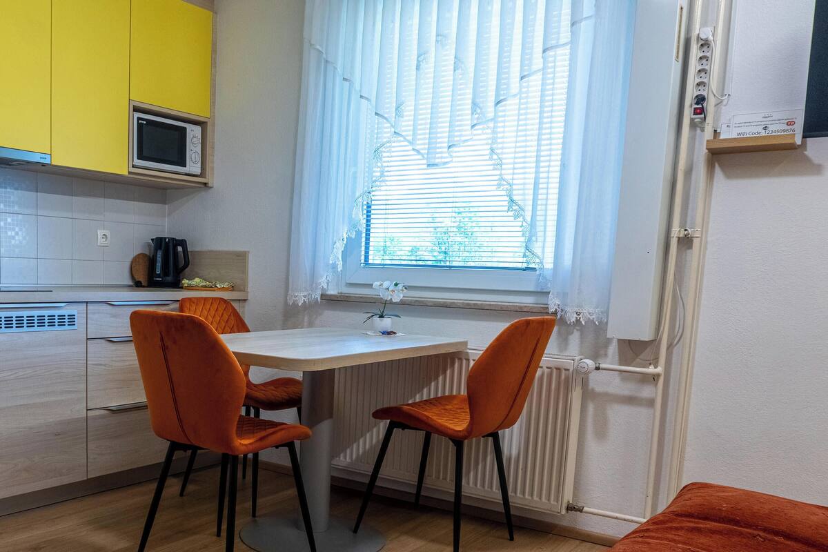Eine moderne Küche mit Mikrowelle, Wasserkocher und einem Fenster mit Jalousien.