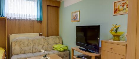 Una sala de estar con sofá, mesa de centro, televisor y aparador.