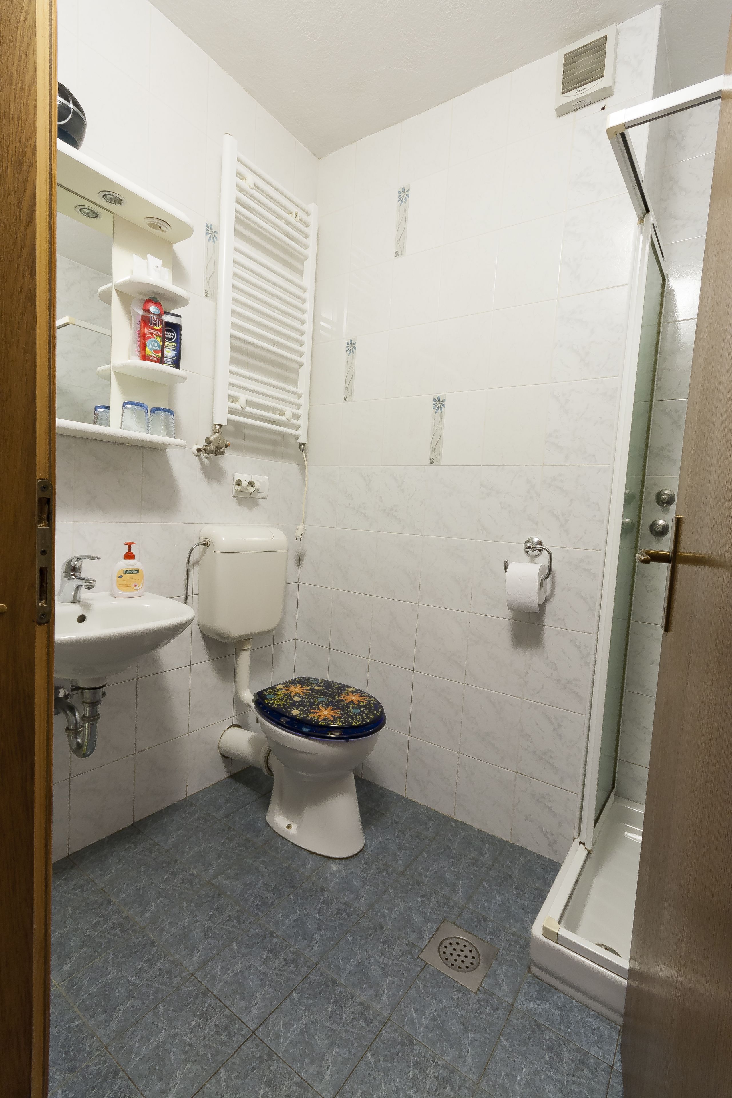 A small bathroom with a toilet, sink, and shower.