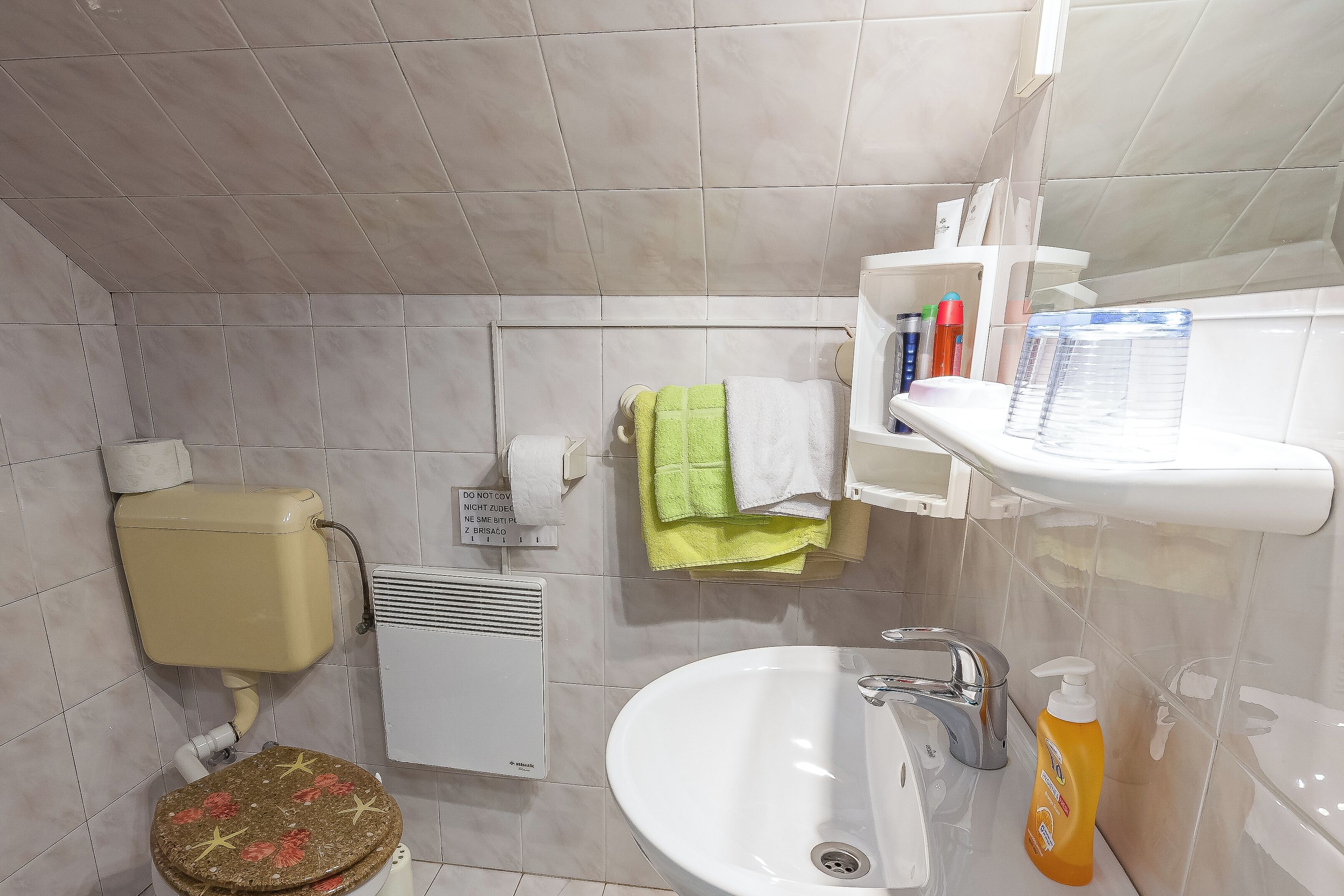 Un baño con inodoro, lavamanos y un estante con artículos de tocador.