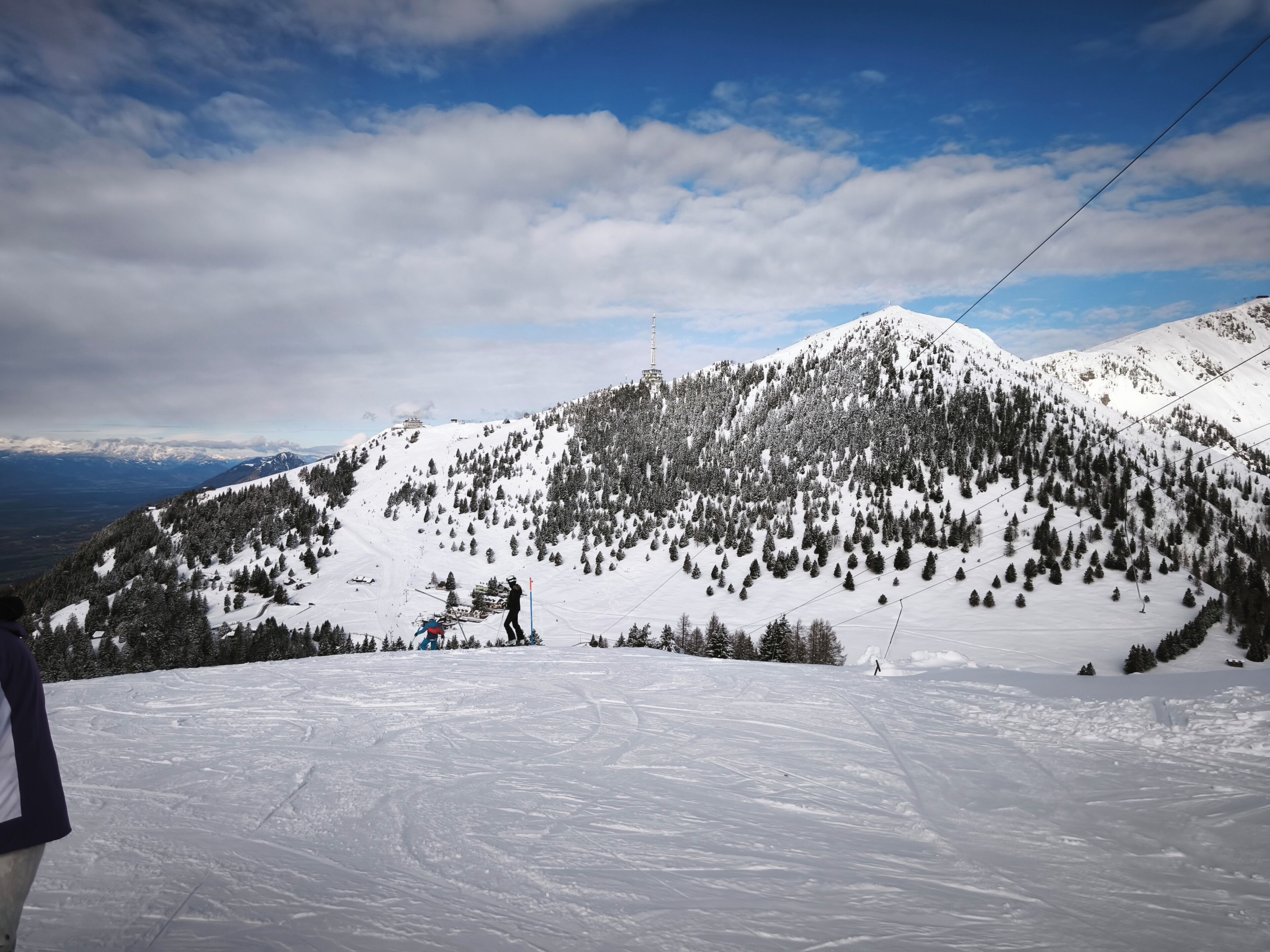 A snowy mountain landscape with ski slopes, a ski lift, and a clear sky.