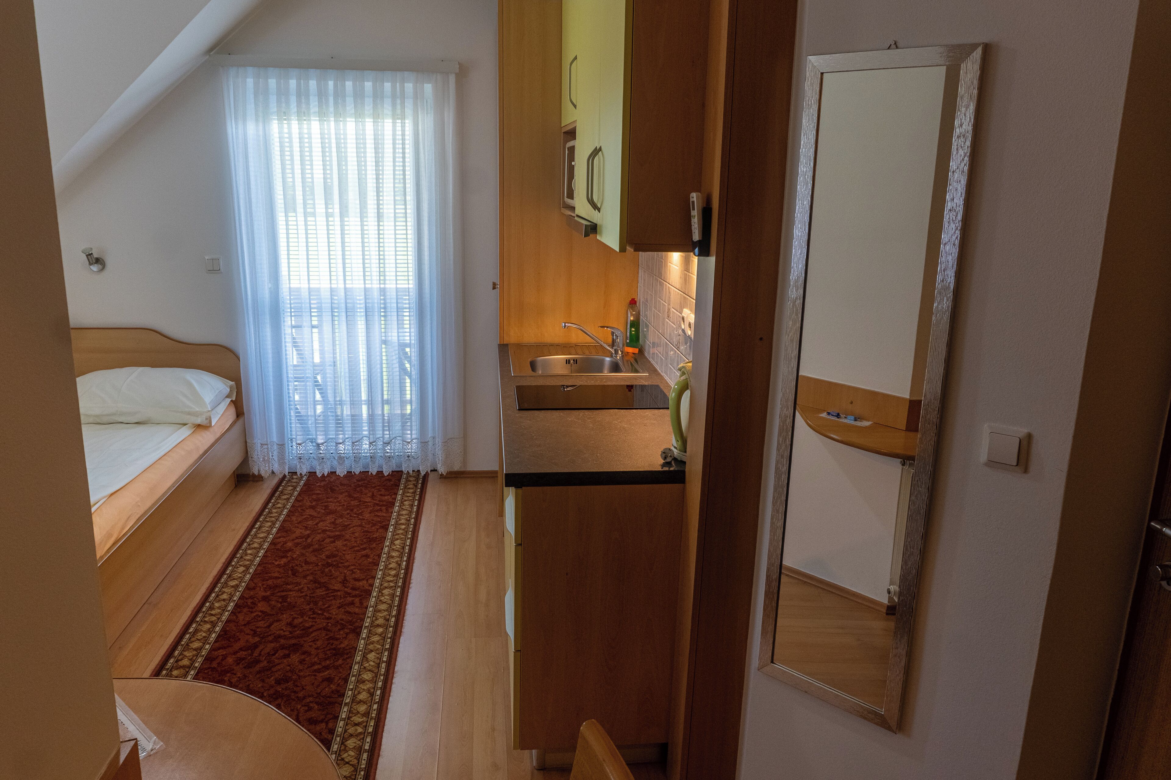 A bedroom with a bed, a small kitchenette, and a bathroom.