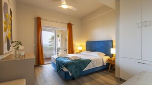 A hotel room with a bed, a nightstand, a lamp, a ceiling fan, a window with curtains, and a view of the outside. - A15- Cliffside Beach Apartment by Dreamalgarve (Lagos)
