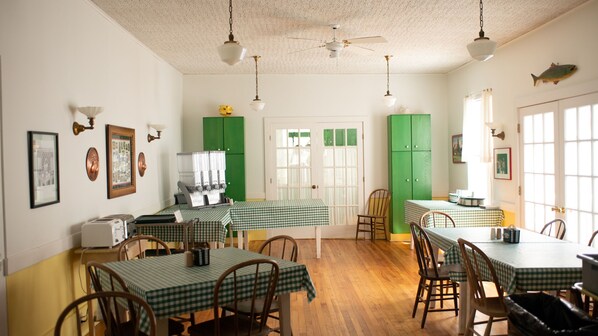 A dining area with checkered tablecloths, wooden chairs, and a green cabinet. - Fountain Point Resort (Lake Leelanau)