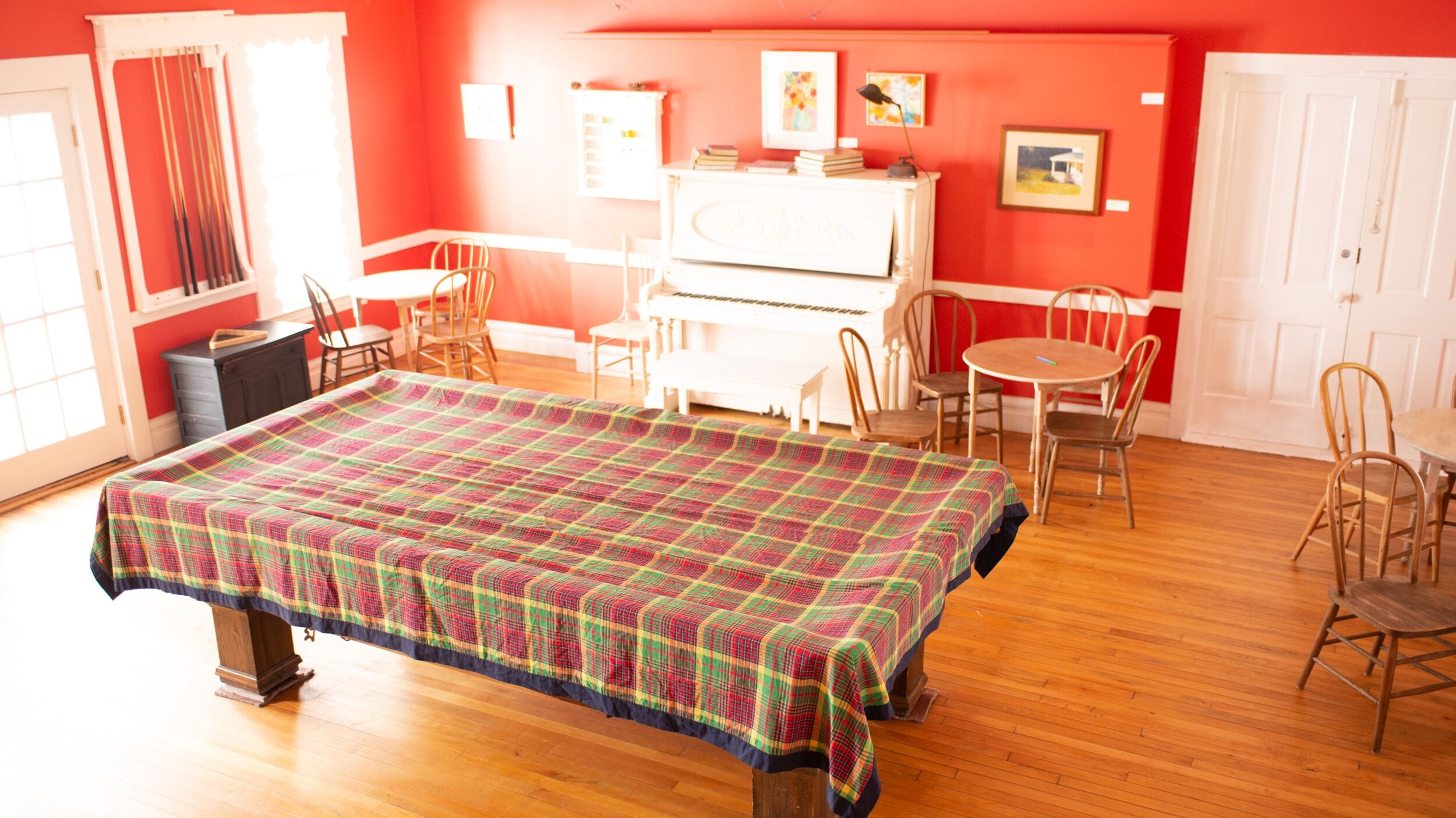 A room with a large bed, a piano, several chairs, and a dining table.