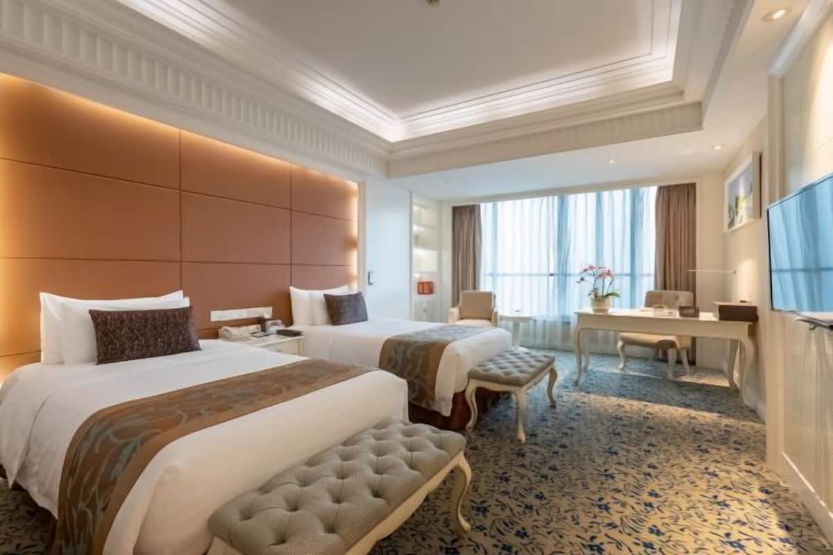 Ein Hotelzimmer mit zwei Betten, einem Schreibtisch und einem großen Fenster.