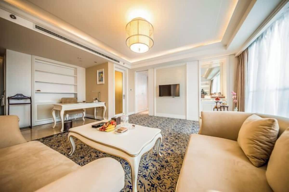 Ein modernes Hotelzimmer mit einer Couch, einem Couchtisch, einem Schreibtisch und einem Fernseher.