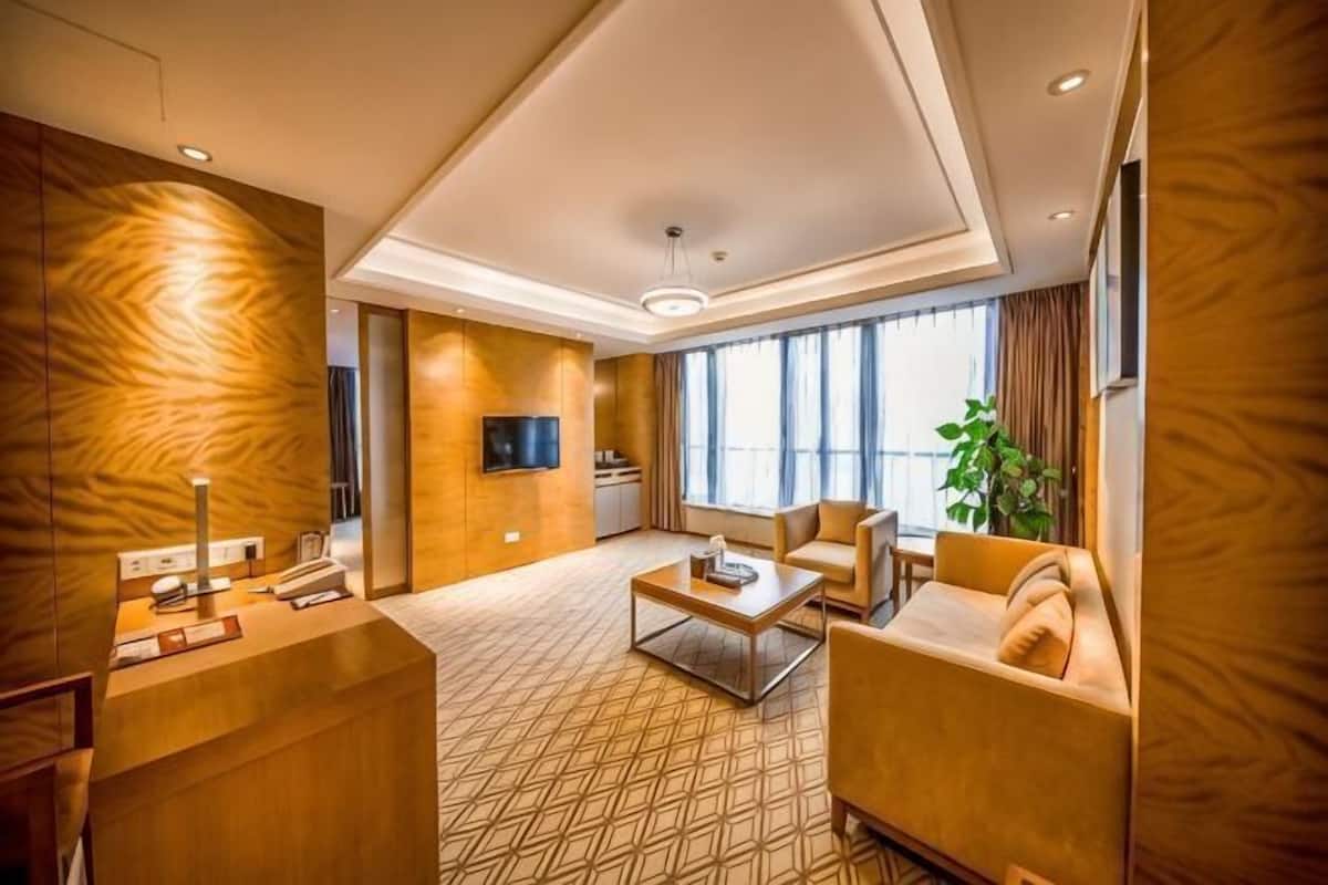 Ein Hotelzimmer mit Sofa, Couchtisch, Fernseher und einem großen Fenster.