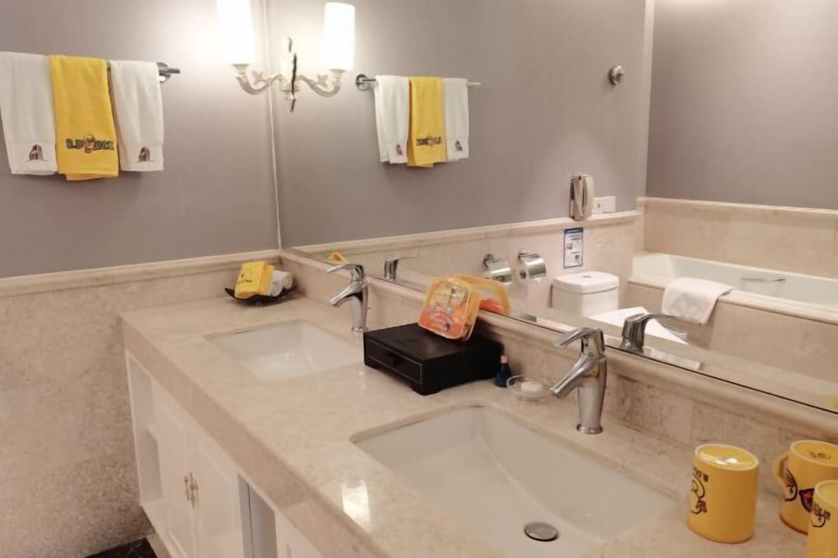 A bathroom with two sinks, a mirror, and towels hanging on the wall.