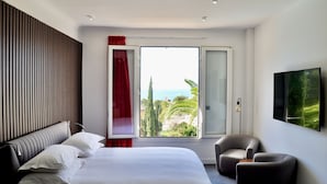 A modern hotel room with a large bed, a seating area, and a view of the sea. - The Address Cassis (Cassis)