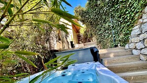 A hot tub surrounded by greenery and stone walls. - The Address Cassis (Cassis)