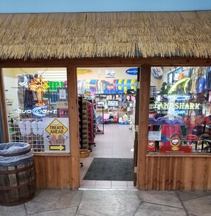 Una fachada con techo de paja, escaparates de vidrio y varios letreros, incluyendo 'BUD LIGHT' y 'LANDSHARK Lager'.