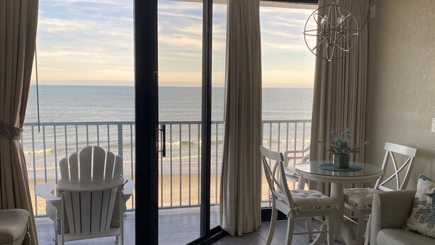 Ein Zimmer mit Blick auf den Strand, einem Glastisch und einem weißen Sofa.