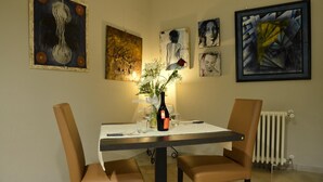 A dining area with a table set for two, surrounded by modern art pieces on the walls. - Albergo Italia (Porto Tolle)