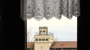 A view through a window with a curtain, featuring a building with a clock and the word "MUNICIPIO" on its facade. - Albergo Italia (Porto Tolle)