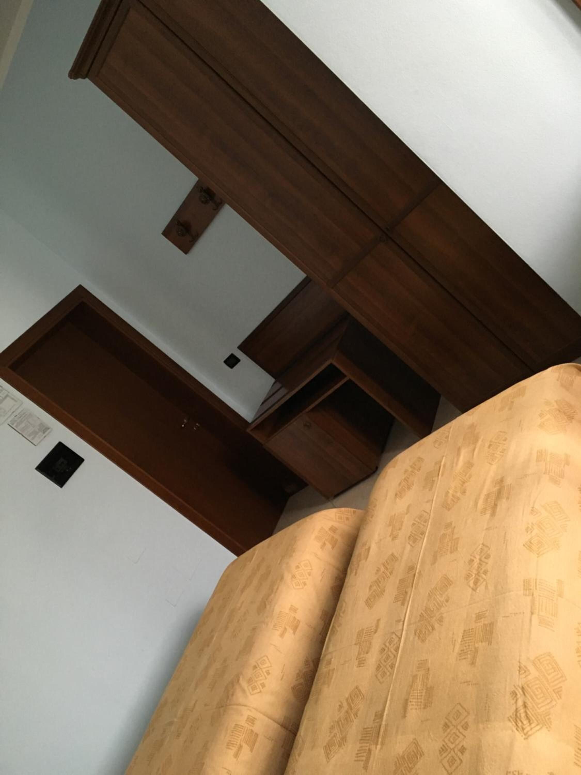 Una habitación con un sofá estampado, vigas de madera en el techo y una pared blanca con un cuadro pequeño.