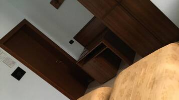 Una habitación con un sofá estampado, vigas de madera en el techo y una pared blanca con un cuadro pequeño.