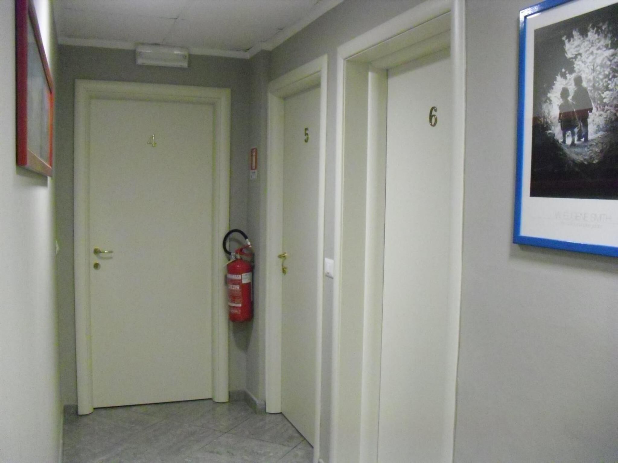 A hallway with doors numbered 4, 5, and 6. A fire extinguisher is mounted on the wall.