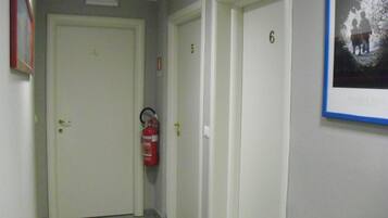 A hallway with doors numbered 4, 5, and 6. A fire extinguisher is mounted on the wall.