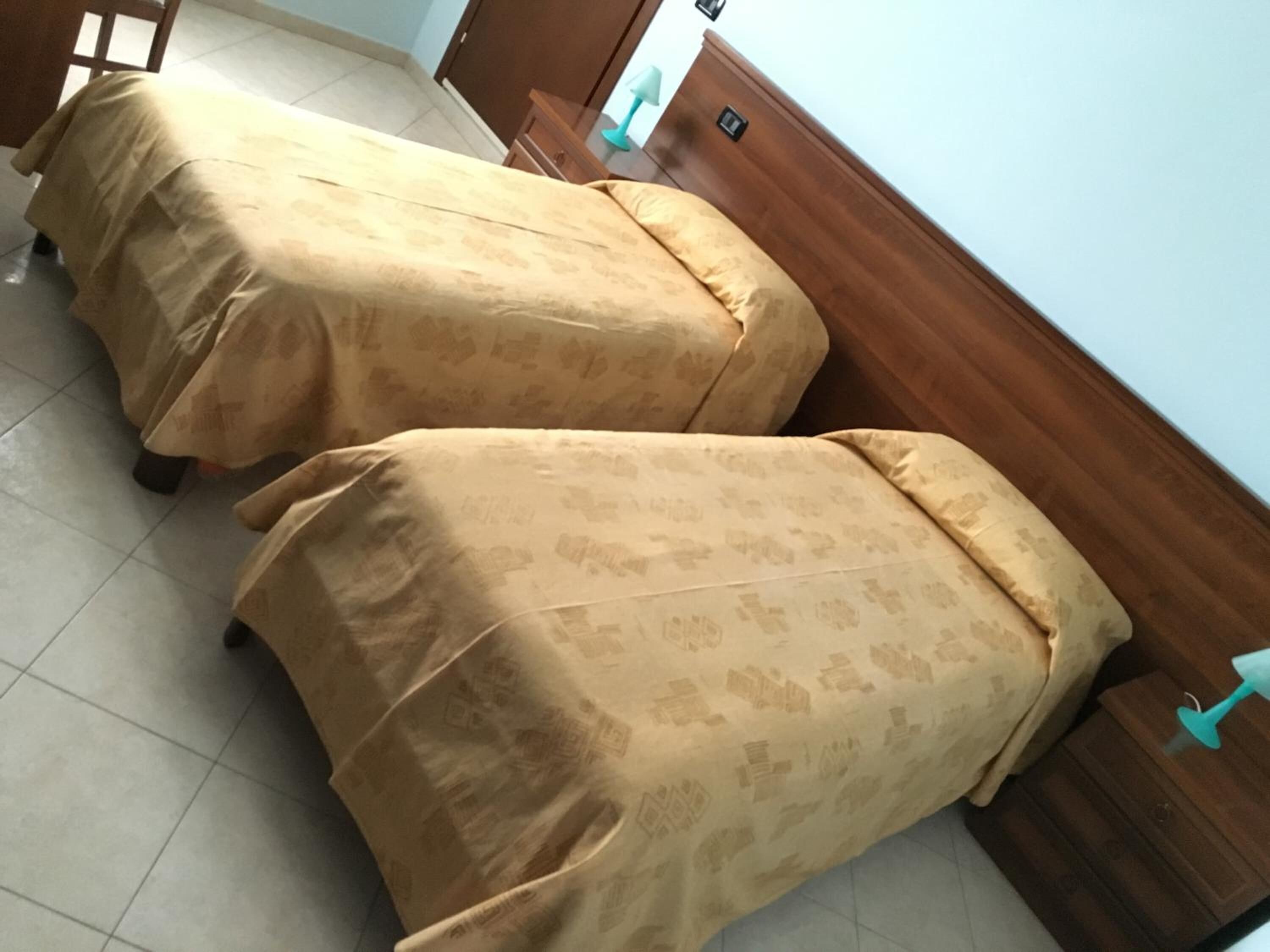 Dos camas con cubrecamas a juego, un cabecero de madera y suelo de baldosas.